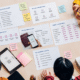 In bird's eye view, a group of people at a table are looking at paperwork related to choosing an ID chip verification provider.
